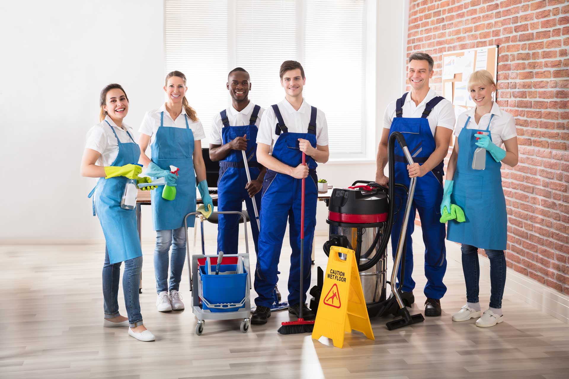 Team of janitors posing with cleaning equipment