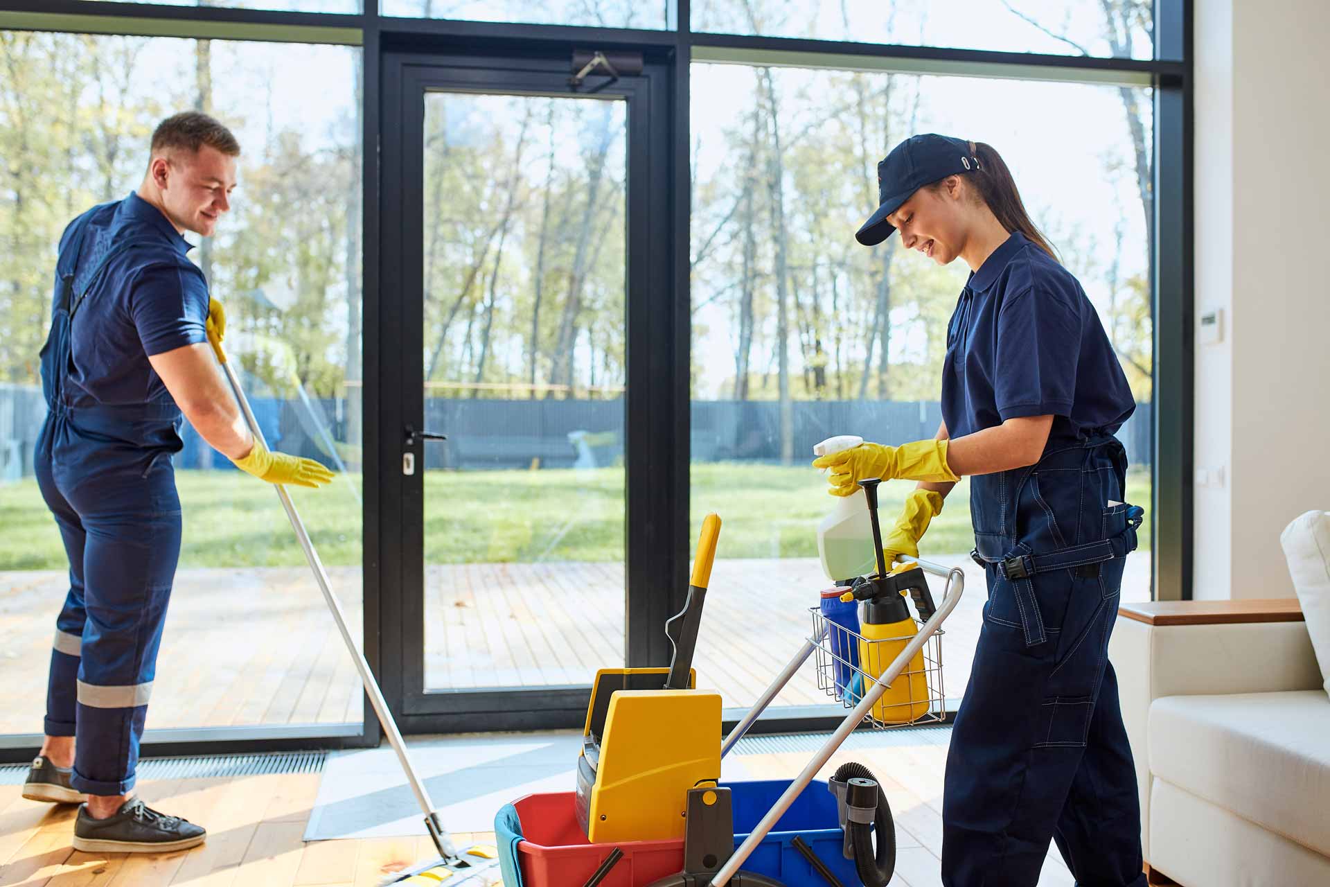 Two uniformed cleaning employees mopping a floor