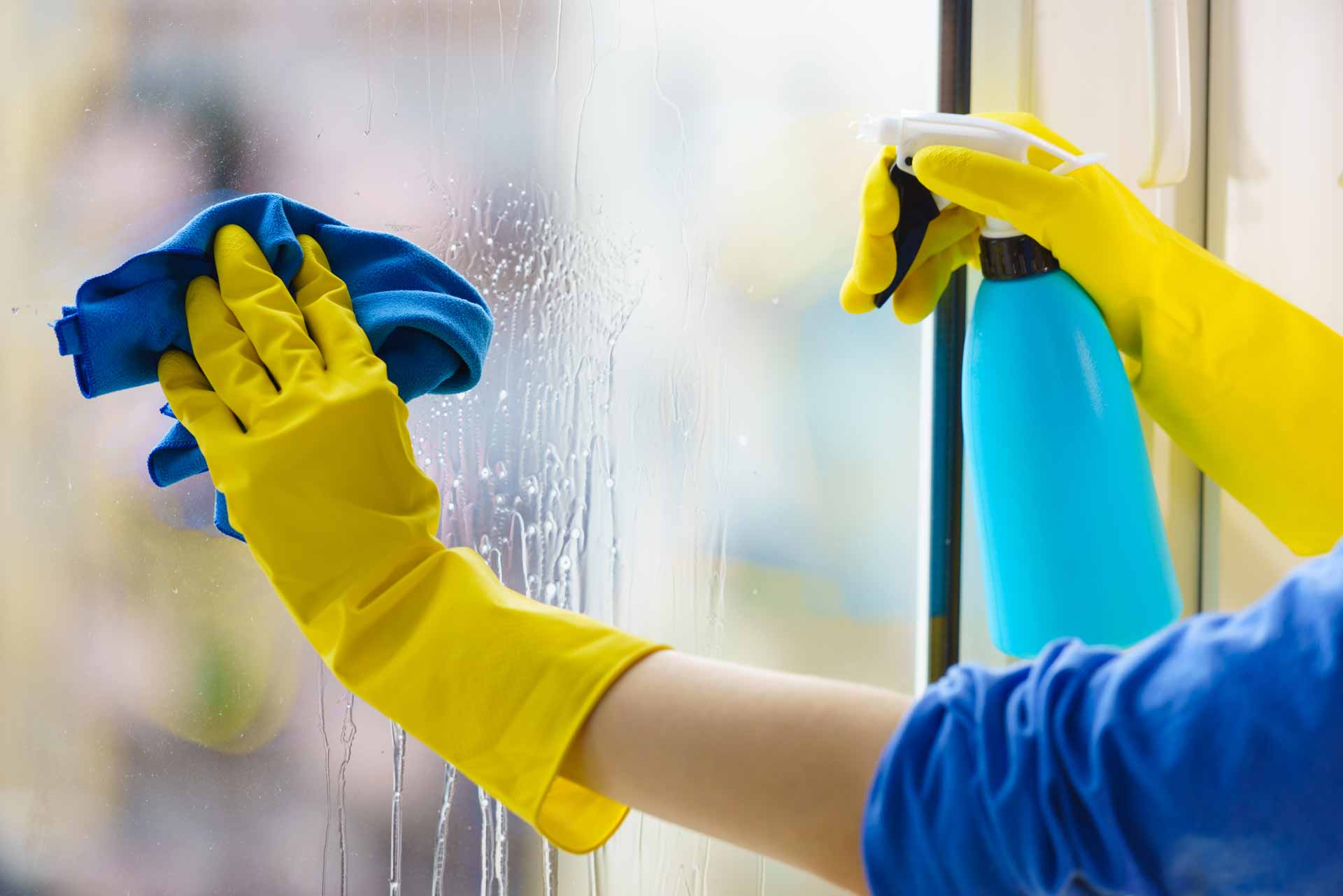 Close up on gloved hands washing window